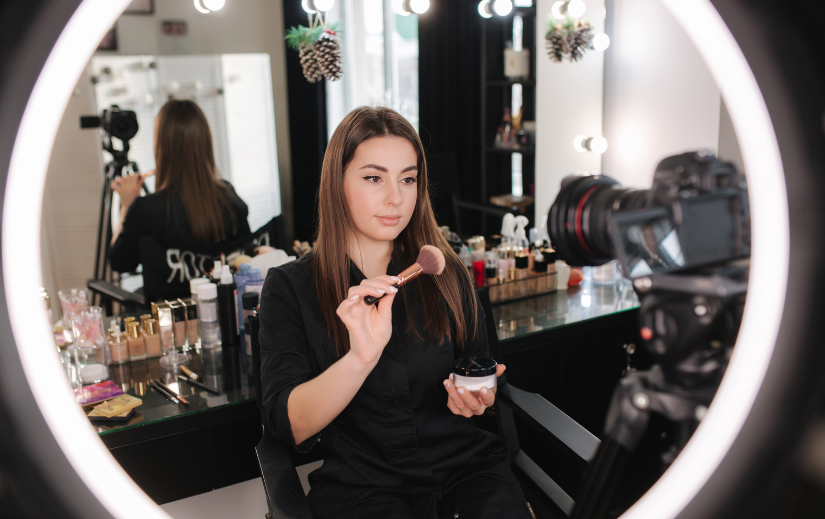 Beauty influencer filming a makeup tutorial for online stores, showcasing trending beauty products under pro lighting.